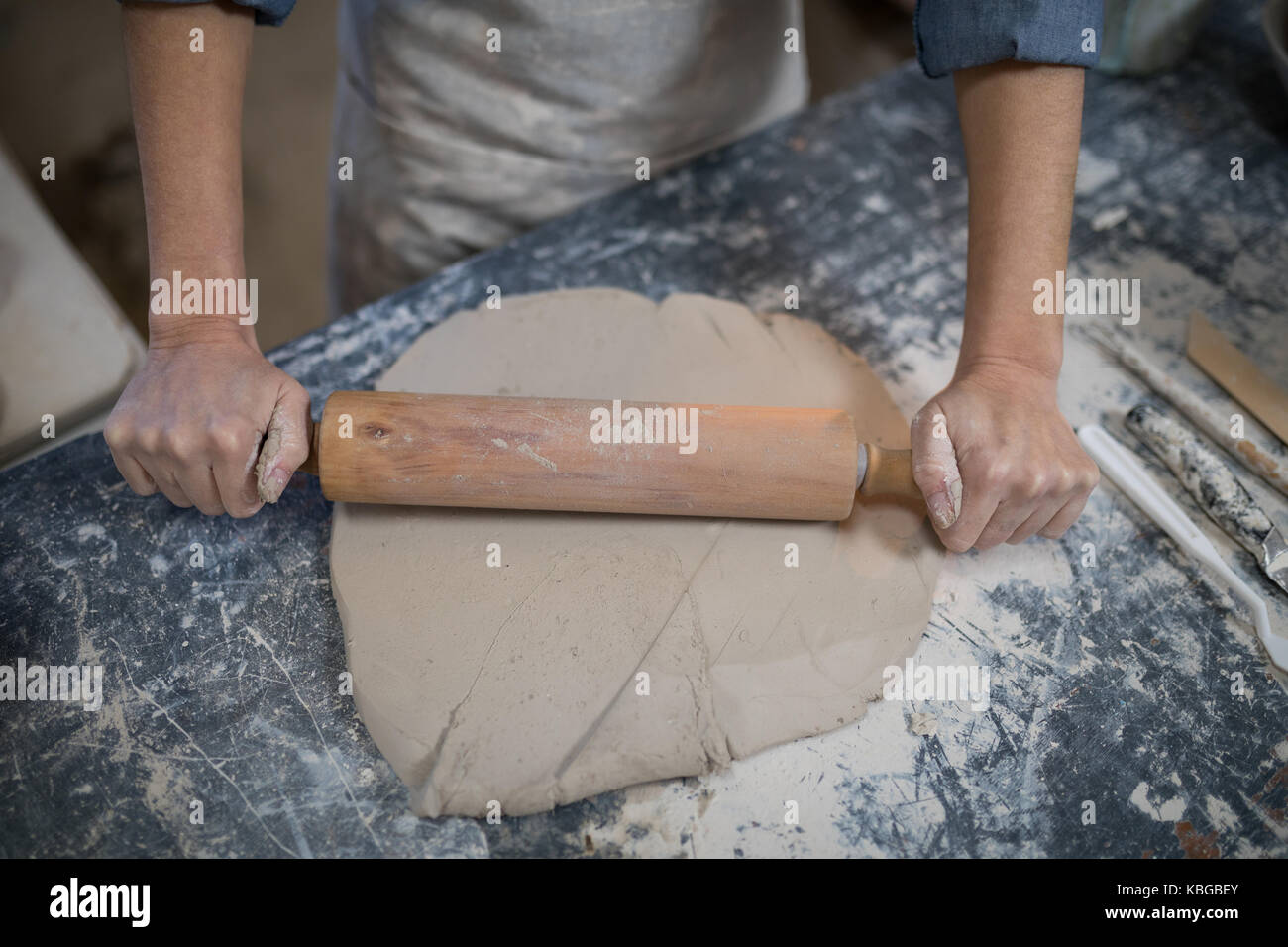 Mid section of female potter flattening the clay with rolling pin Stock Photo