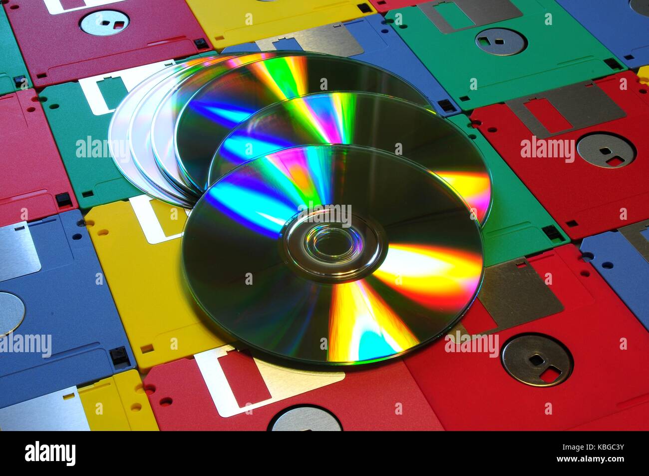 Old diskette 5 25 inches with 3.5 floppy disks of various colors with modern DVD. Background Stock Photo