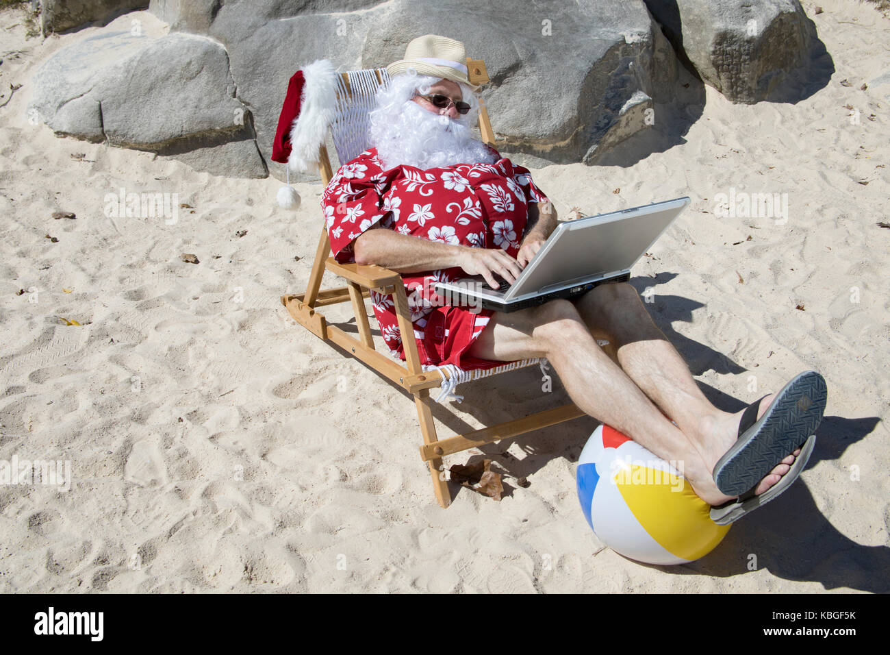 Santa Claus in red swimming trunks ans Hawaiian shirt lounging on sandy ...