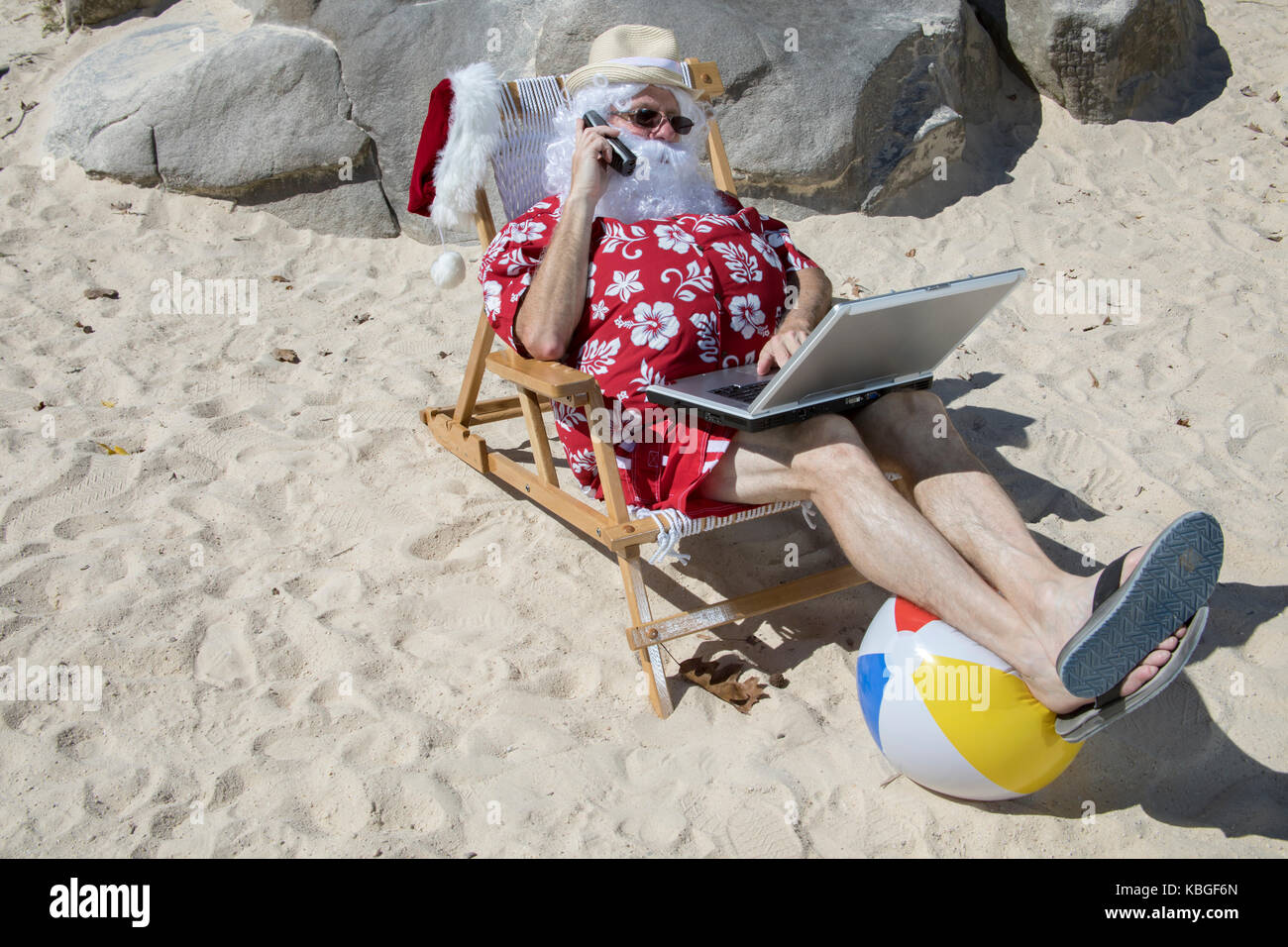 Santa Claus in red swimming trunks ans Hawaiian shirt lounging on sandy ...