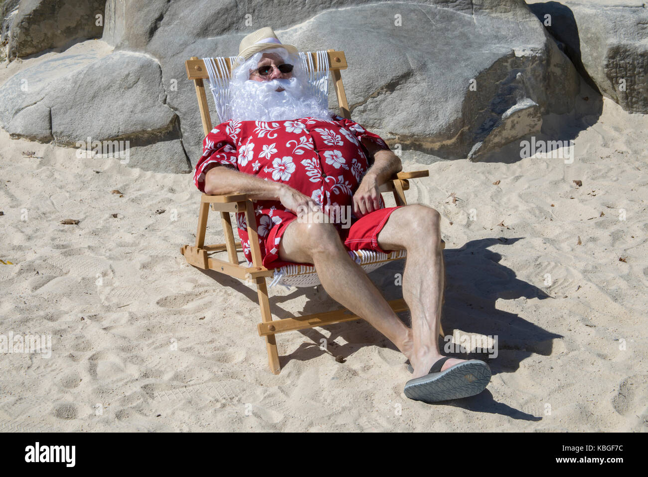 Santa Claus in red swimming trunks ans Hawaiian shirt lounging on sandy  beach with straw hat and sunglasses Stock Photo - Alamy