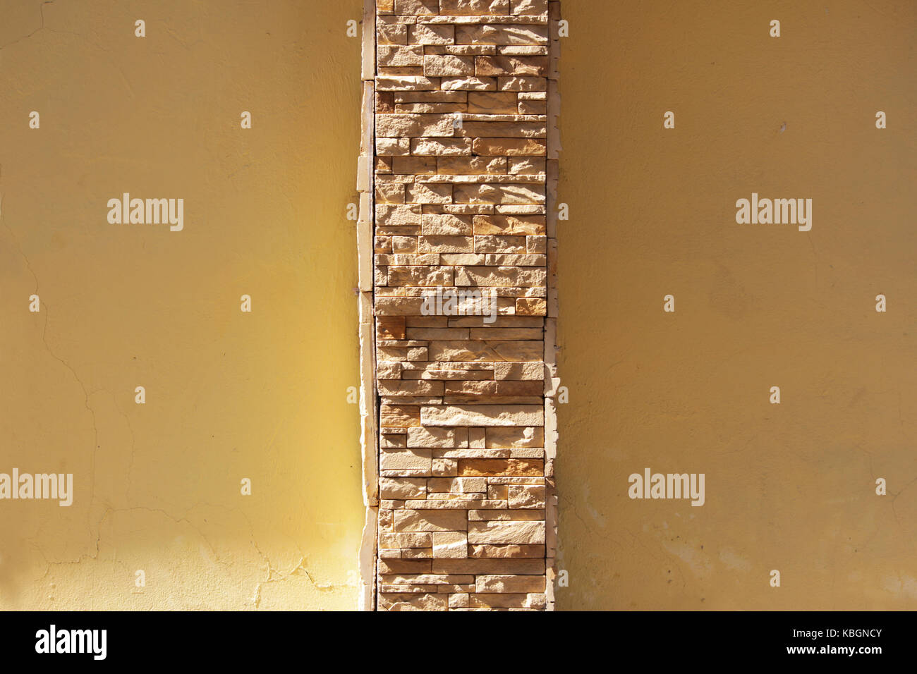 beige plastered wall with an insert of natural limestone of the same color. Stock Photo