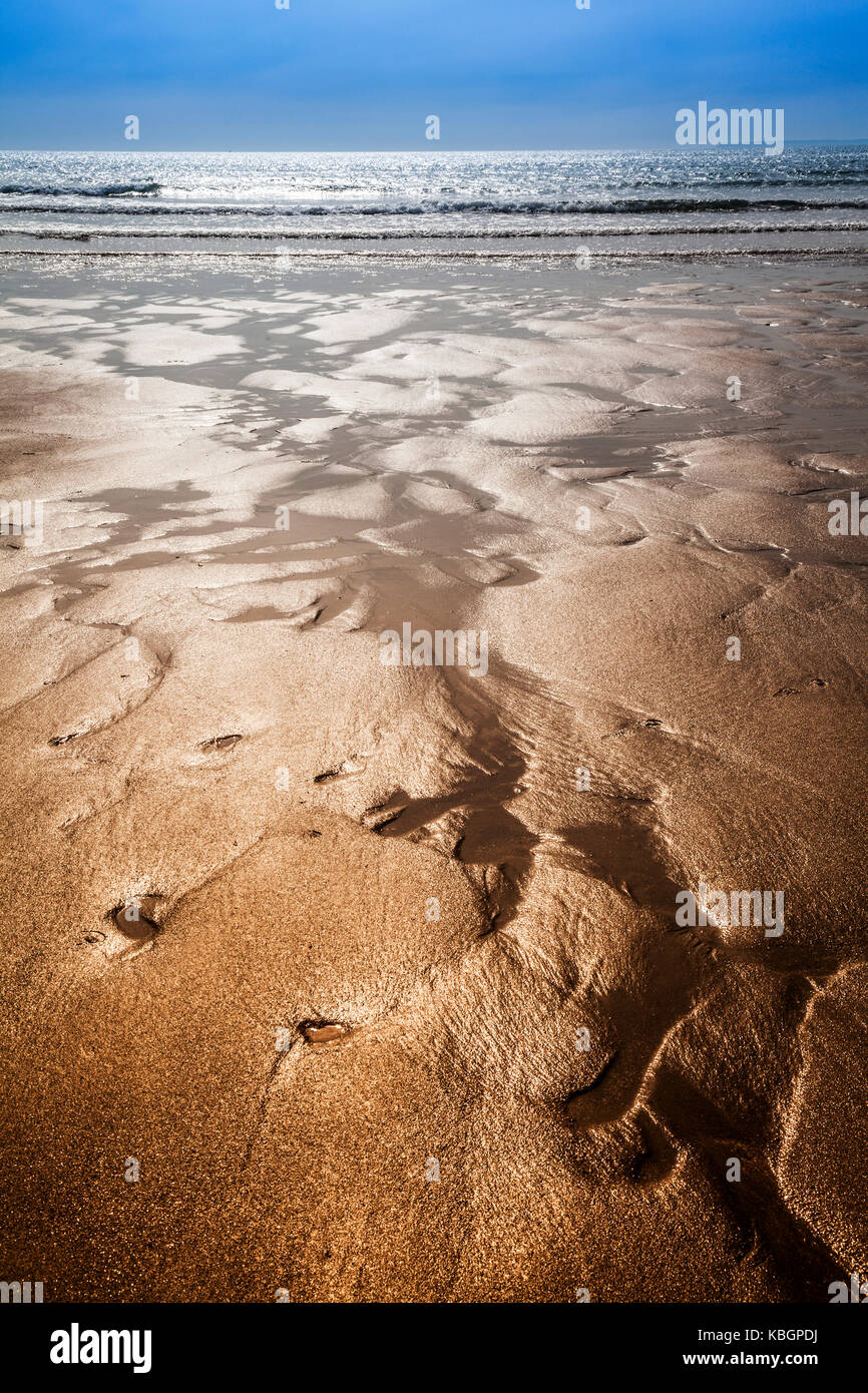 Glistening sand rivulets form abstract patterns on the beach Stock