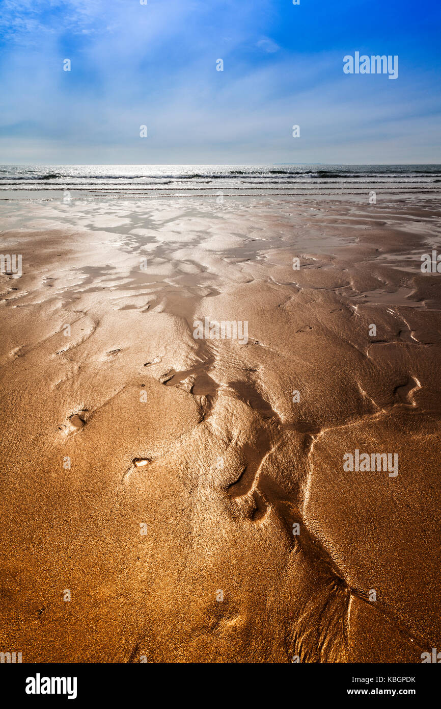 Glistening sand rivulets form abstract patterns on the beach. Stock Photo