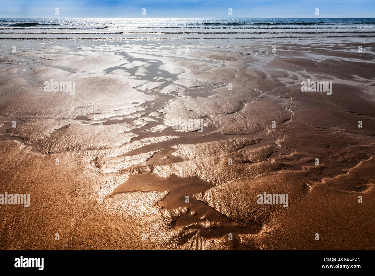 Glistening sand rivulets form abstract patterns on the beach Stock