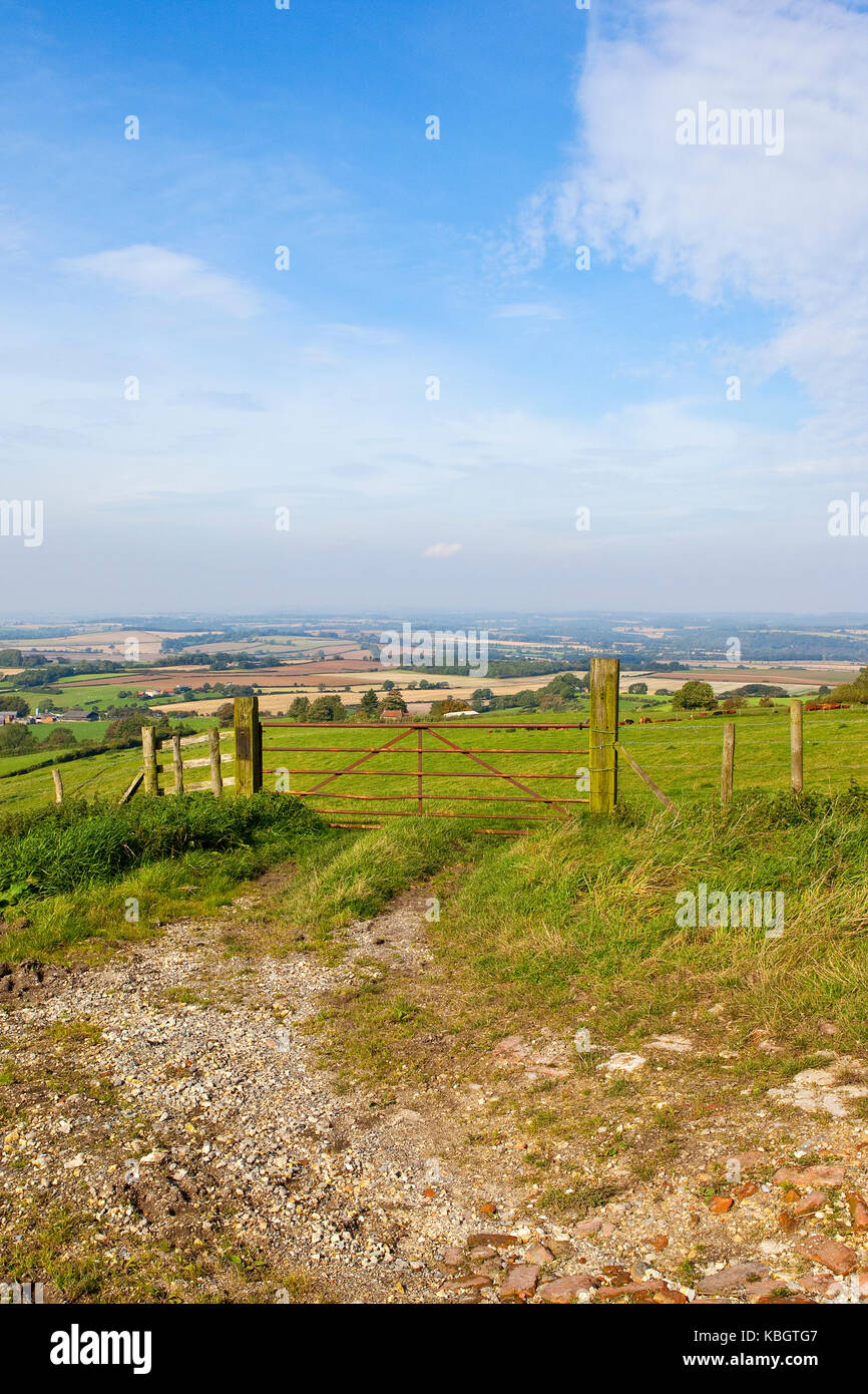a metal farm gate and fence overlooking meadows and patchwork fields ...
