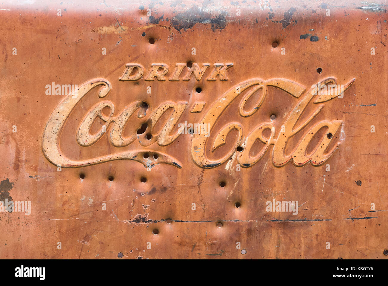 Old rusted coca cola sign with bullet holes. UK Stock Photo