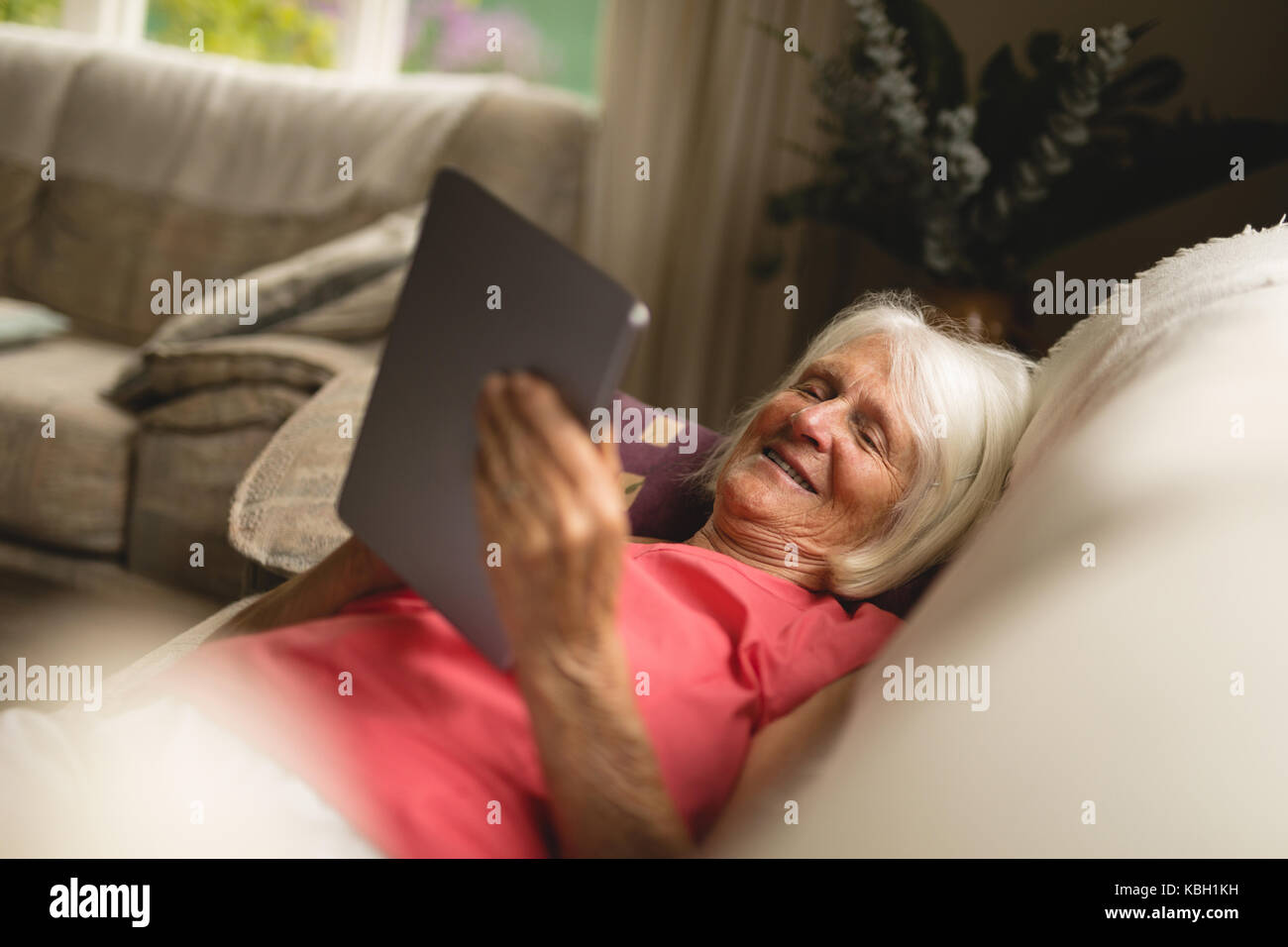 Senior woman using digital tablet on sofa in living room Stock Photo ...