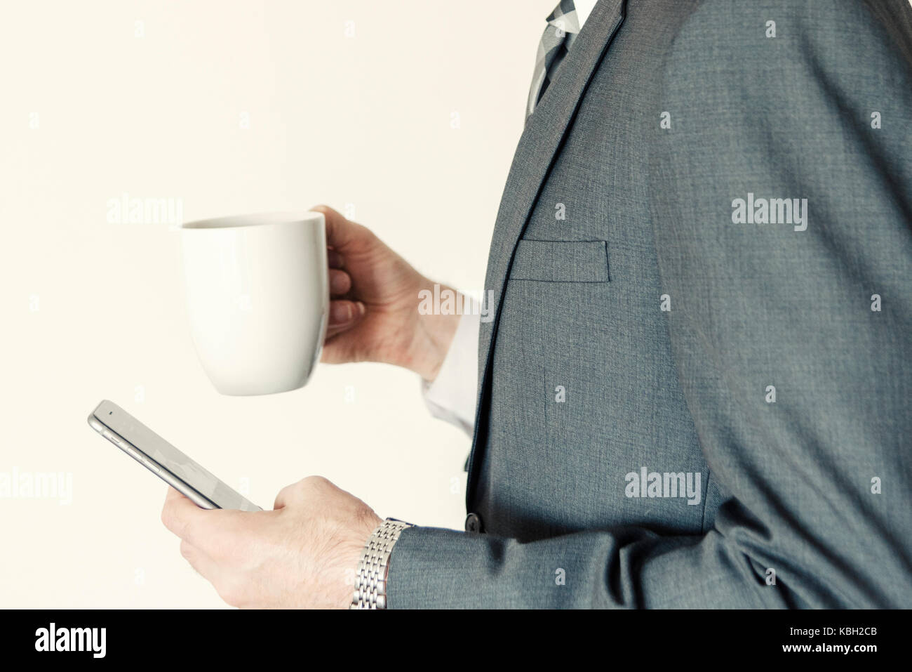 Headless Professional businessman profile side view using smart mobile phone while holding a cup of coffee in office horizontal. Stock Photo