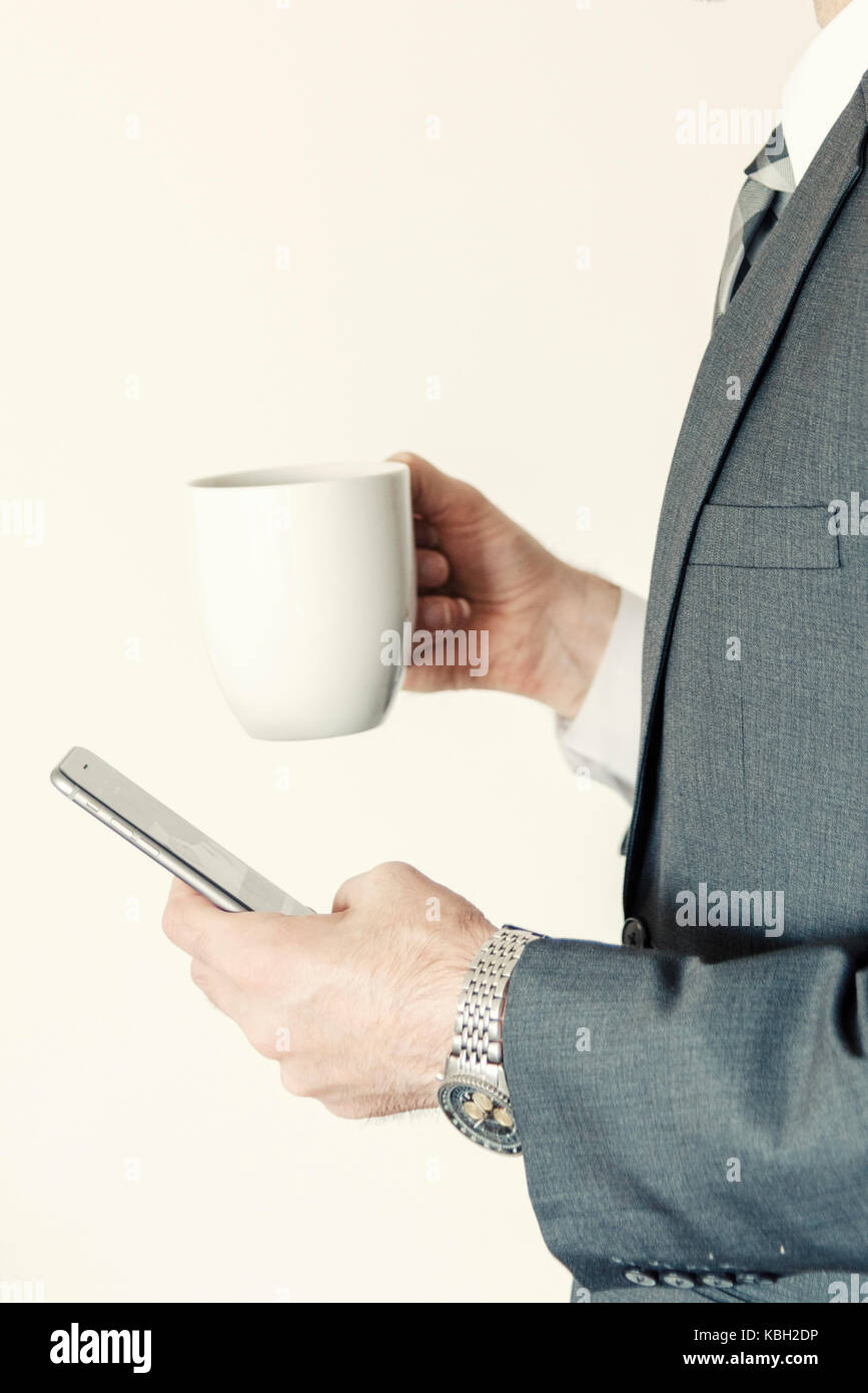 Headless Professional businessman profile side view using smart mobile phone while holding a cup of coffee in office portrait vertical. Stock Photo