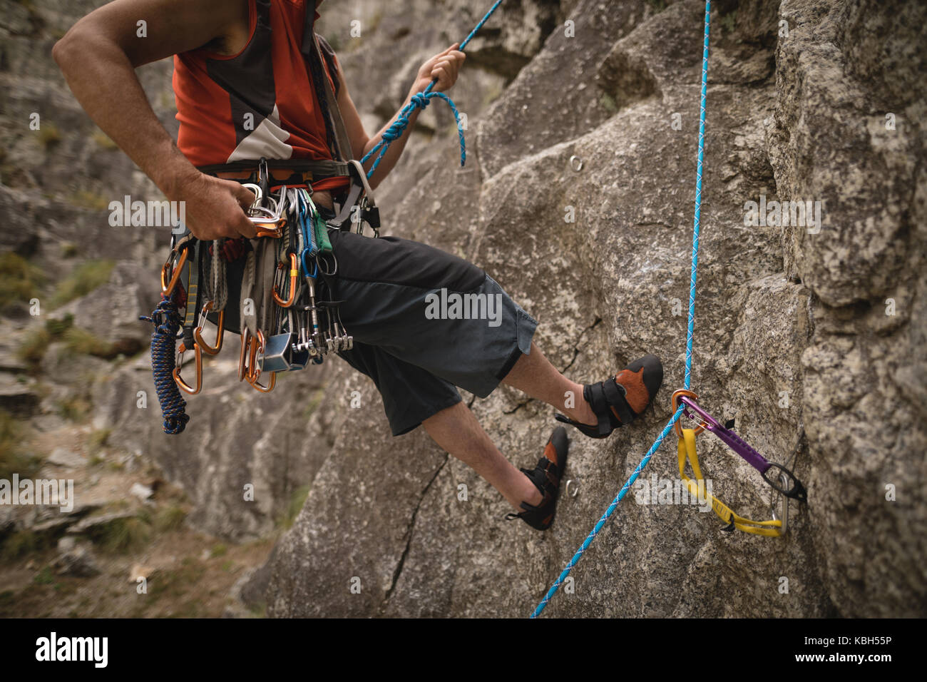 Low section of man with various safety equipment climbing mountain