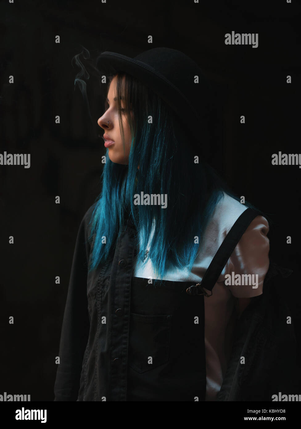 Emo girl smoking cigarette.Street punk or hipster woman with blue colorful  dyed hair, hat, piercing,lenses,ears tunnels and unusual hairstyle stands i  Stock Photo - Alamy