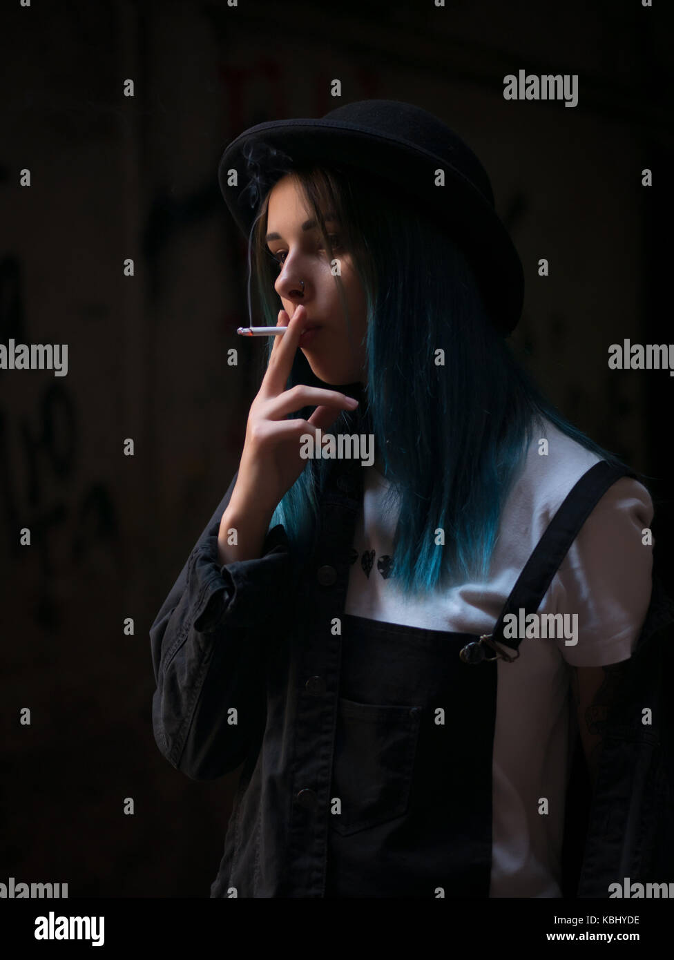 græs plejeforældre hastighed Emo girl smoking cigarette.Street punk or hipster woman with blue colorful  dyed hair, hat, piercing,lenses,ears tunnels and unusual hairstyle stands i  Stock Photo - Alamy