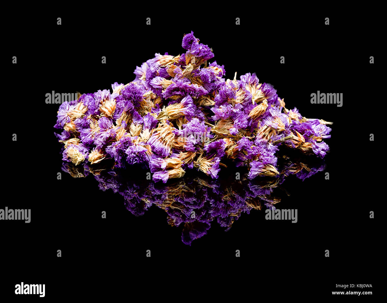 Flower tea. Chinese tea additive for brewing. On a black glossy background with real reflection. Pile of dried flowers Limonium sinuatum, statice, sea Stock Photo