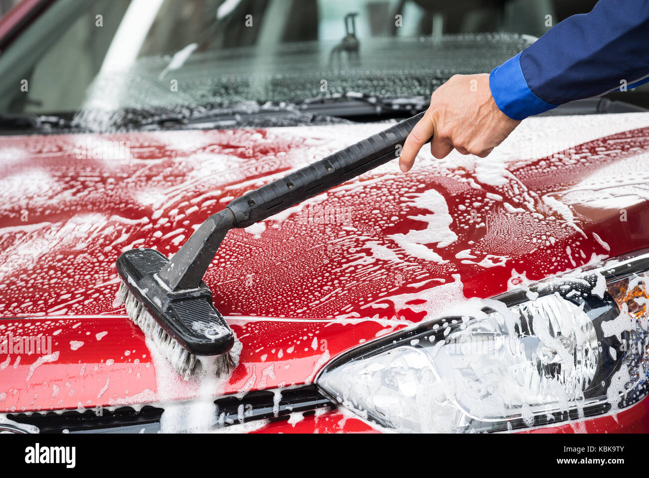Cropped image of mature washer cleaning red car at service station Stock Photo