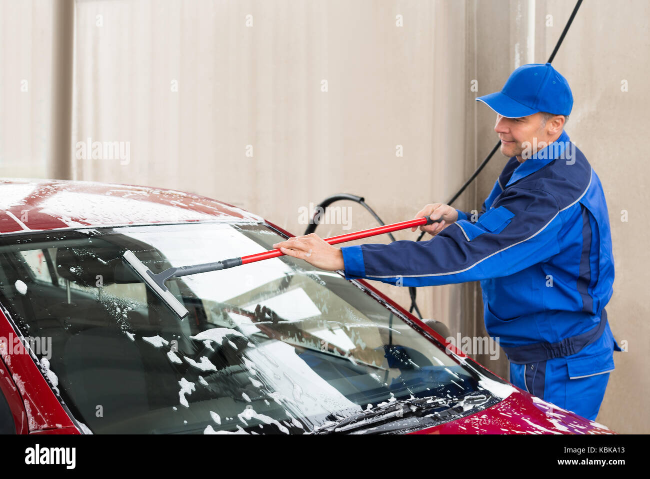 Cropped image of manual worker washing windshield of car at service station Stock Photo