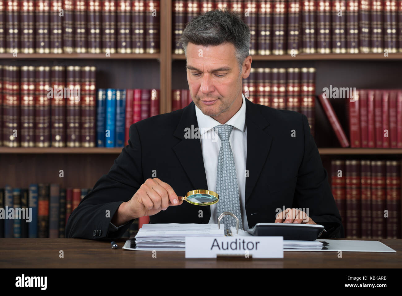 Mature male auditor scrutinizing financial documents at table in office Stock Photo