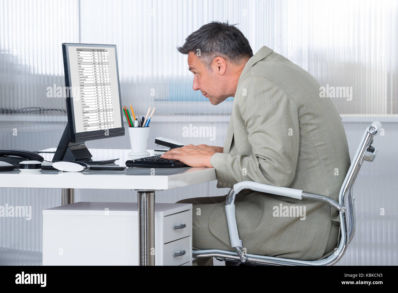 Side view of concentrated businessman using computer at desk in office ...