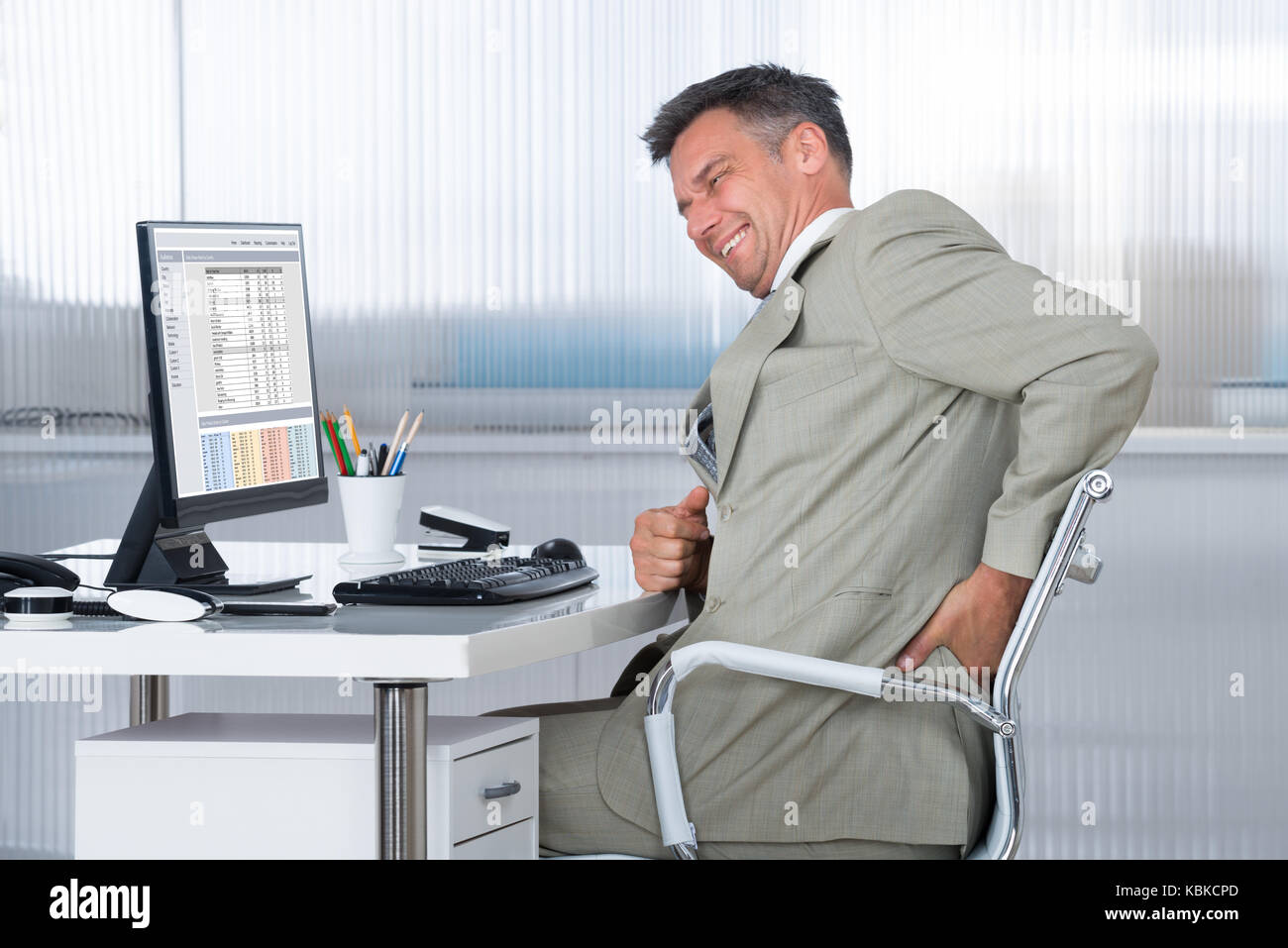 Side View Of Accountant Suffering From Back Pain At Desk In Office