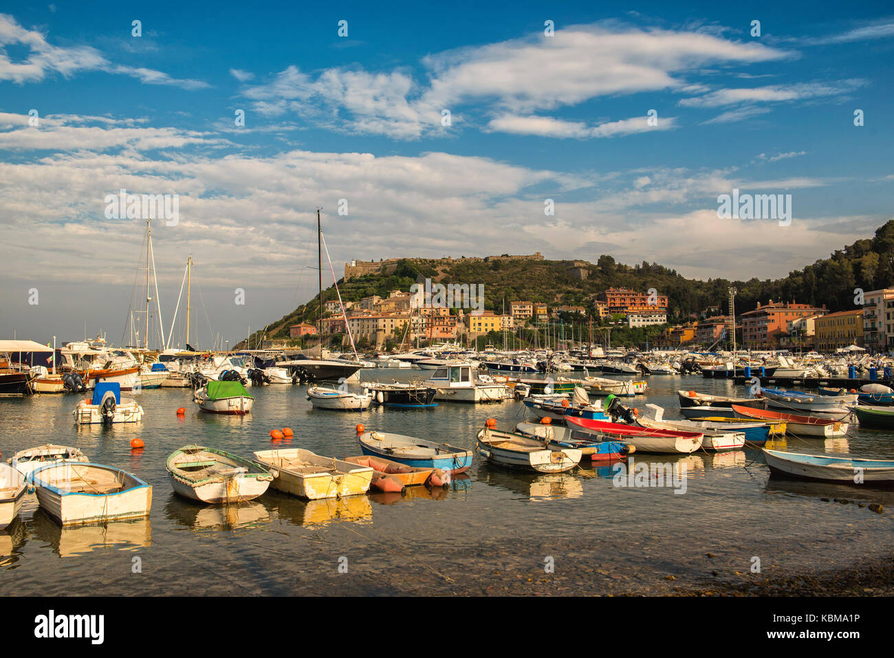 Porto Ercole, Monte Argentario, Tuscany. The harbor with small fishing boats of Porto d'Ercole with the backdrop of the old country and beautiful sky Stock Photo