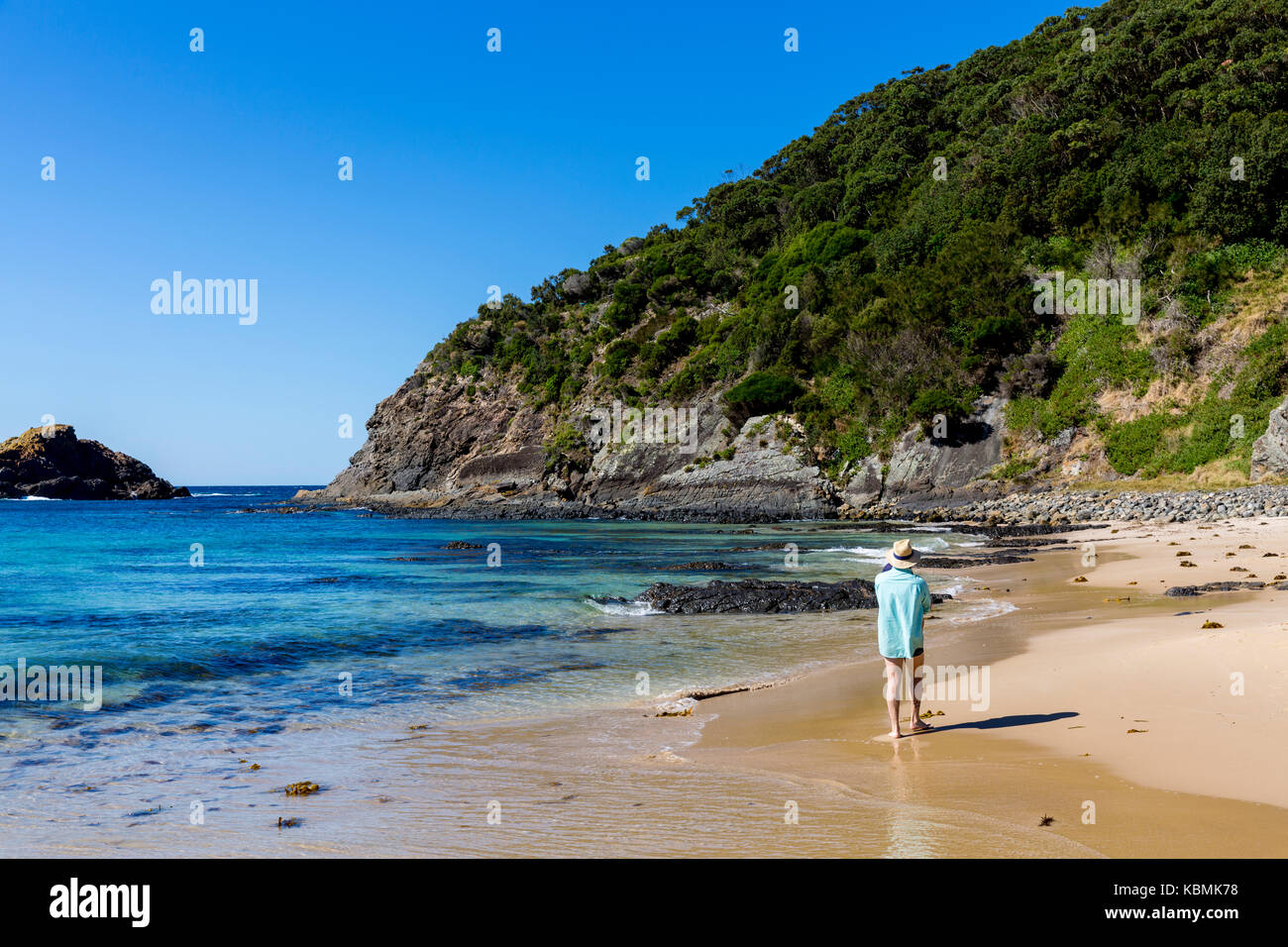 Man carrying a baby walking along Boat Beach at Seal Rocks on the mid north coast of New South Wales,Australia Stock Photo
