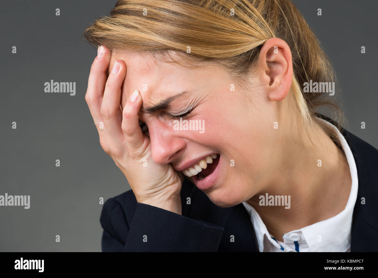 Closeup of young businesswoman crying over gray background Stock Photo