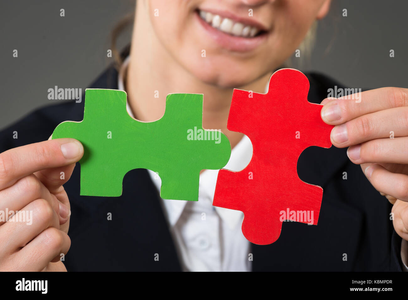 Midsection of businesswoman solving jigsaw puzzle over gray background Stock Photo