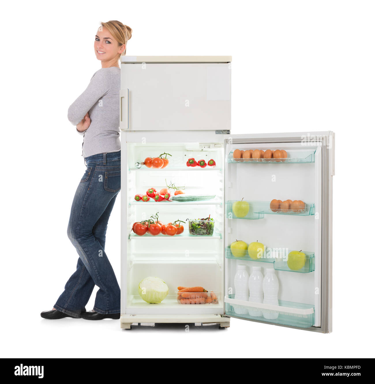 Portrait of confident young woman leaning on open refrigerator over
