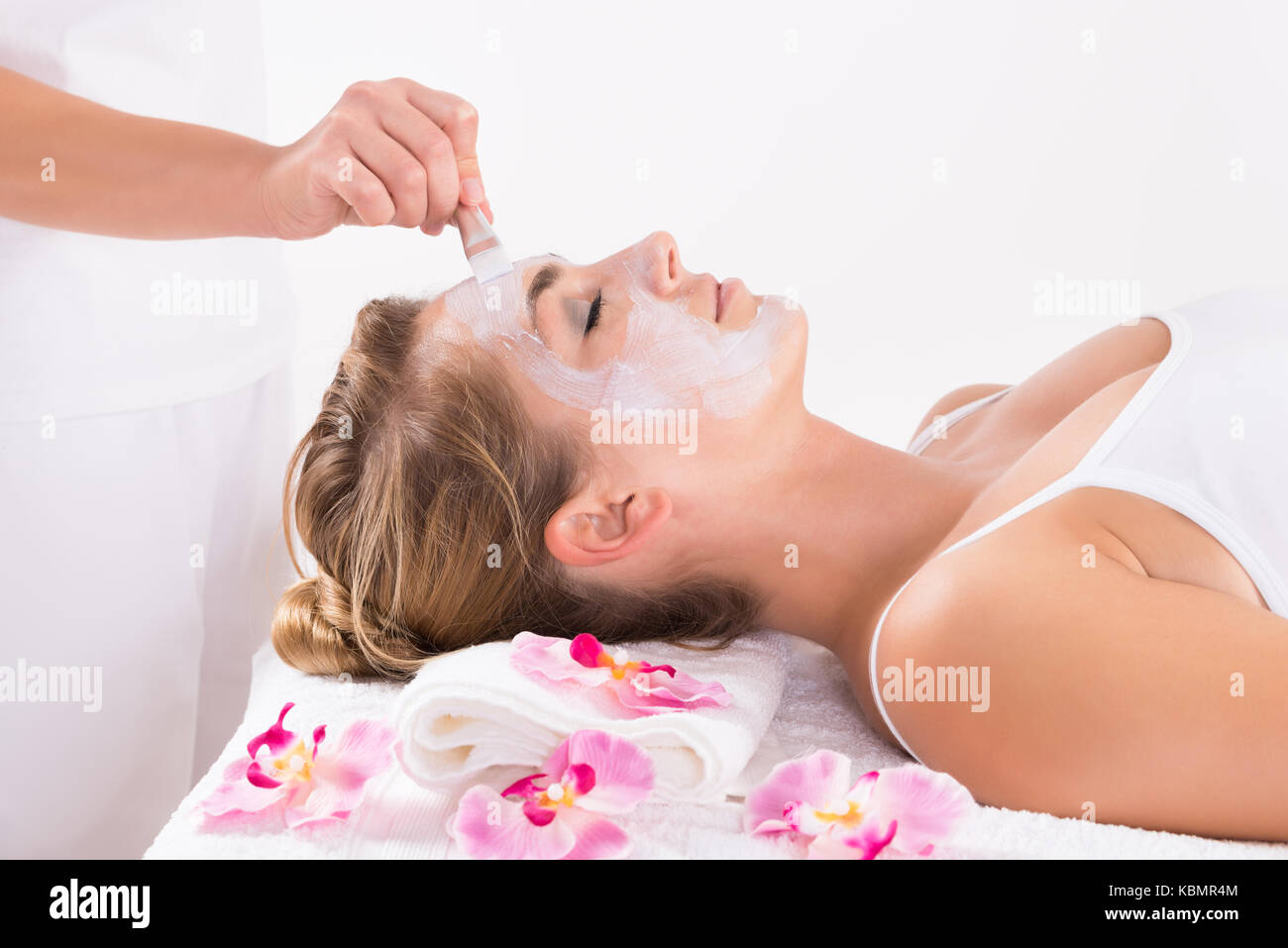 Cropped image of beautician applying mask on customer's face at salon Stock Photo