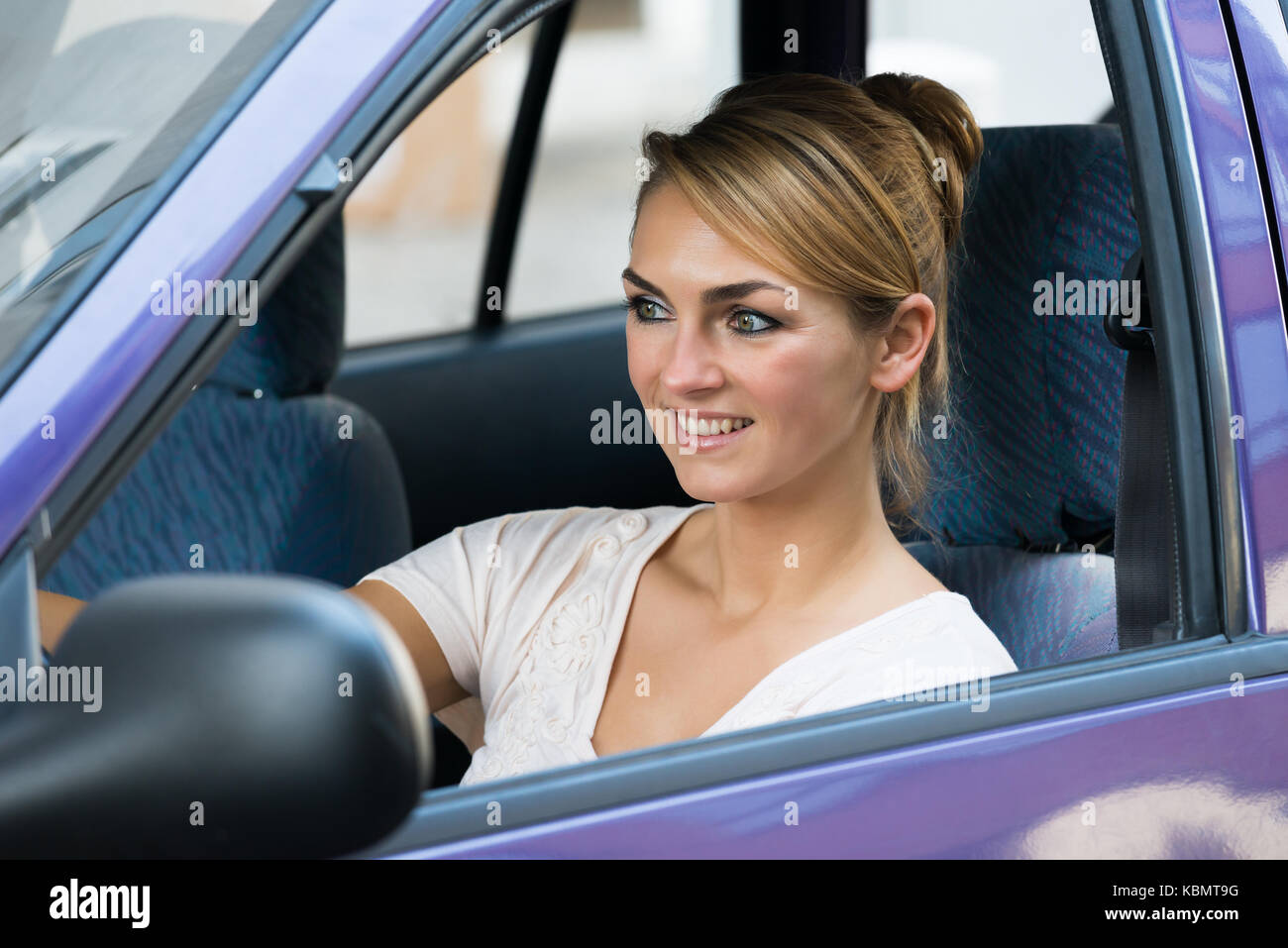 Smiling beautiful young woman driving her first car Stock Photo