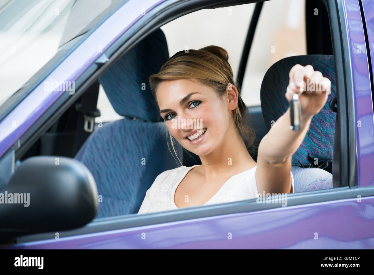 Portrait of happy young woman showing key in new car Stock Photo - Alamy