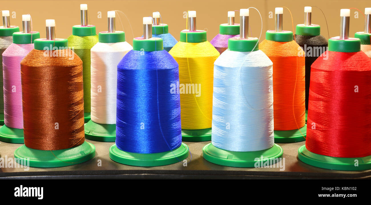 many colorful spools of thread in dressmaking factory and industrial ...