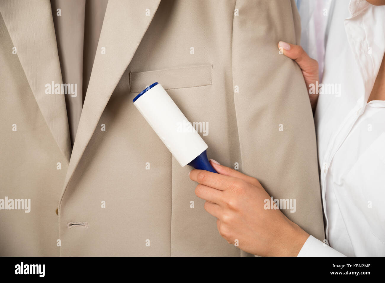 Close-up Of Woman Cleaning Coat With Adhesive Roller Stock Photo