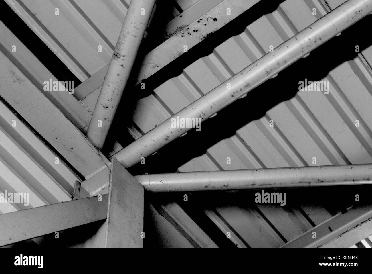 Formalist Photography. Simple black and white photograph of metal industrial architecture with a sunburst of metal girders converging bottom left. Stock Photo