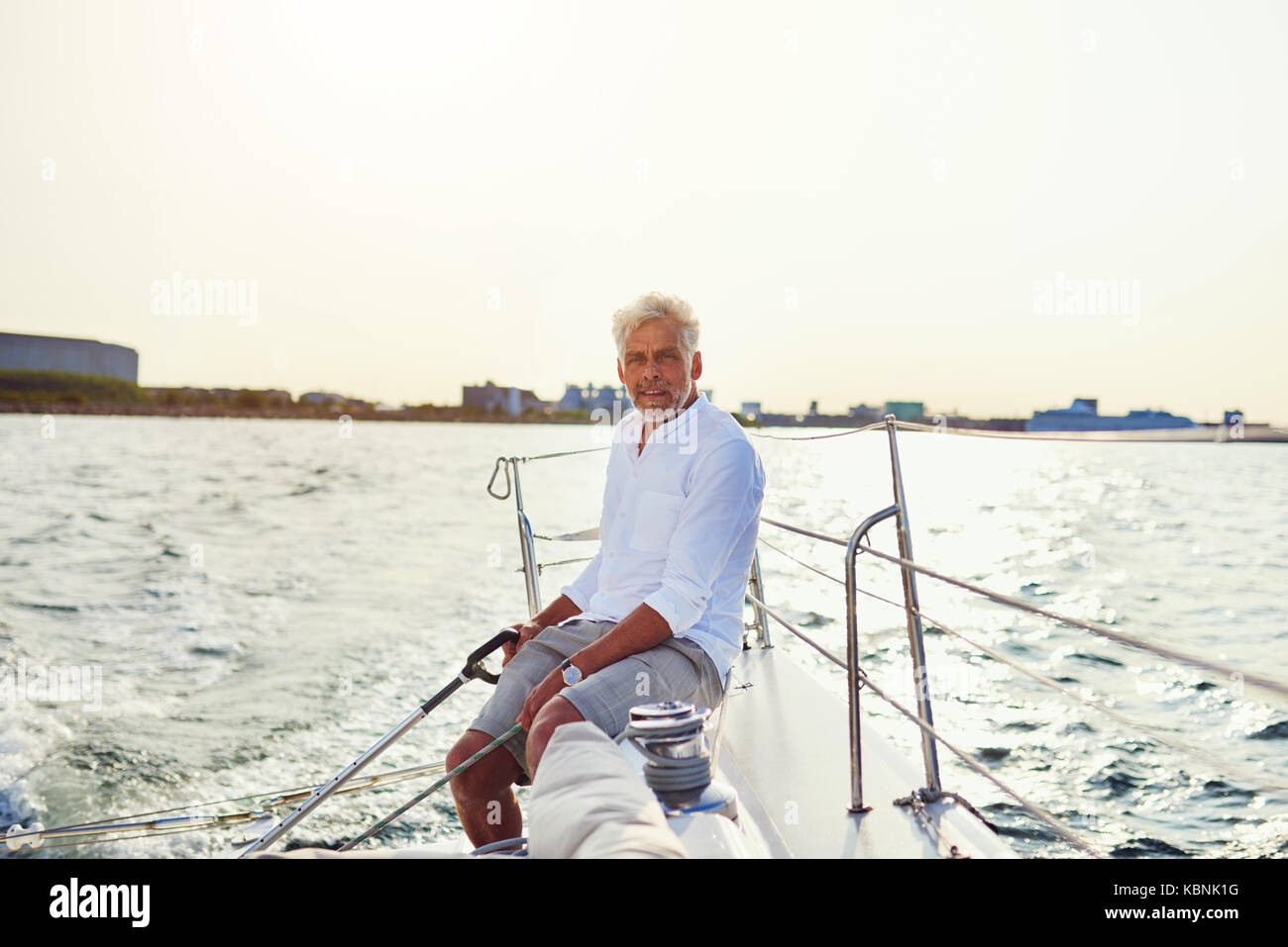 Mature man sitting on the deck of a boat while enjoying a sunny day ...