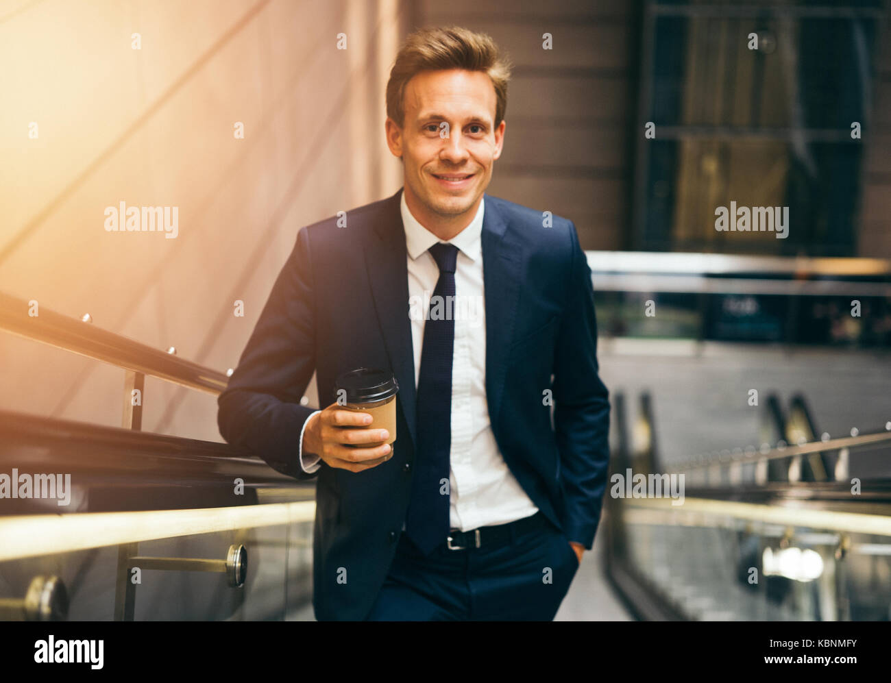 Confident young businessman smiling while drinking a coffee and riding ...