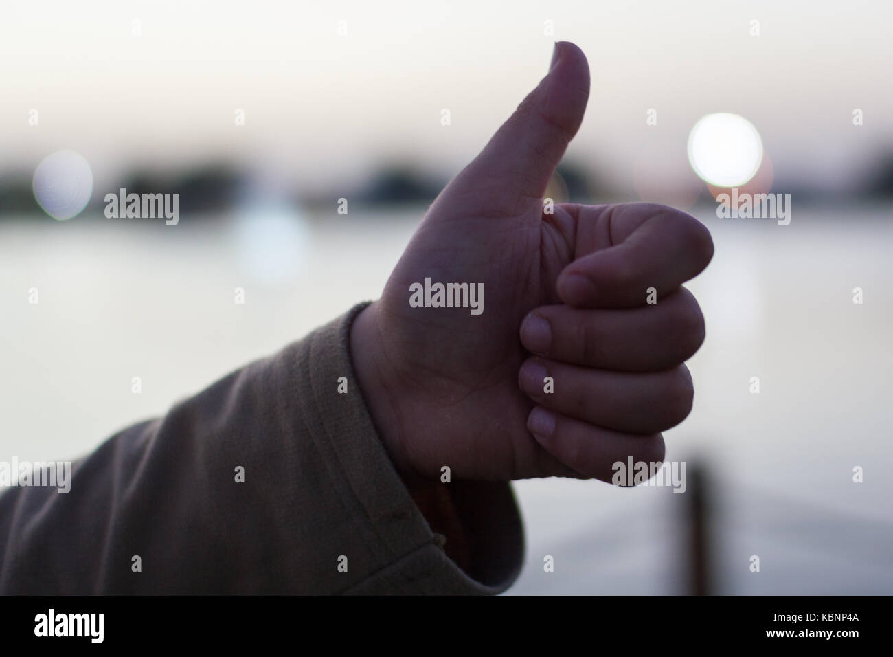 Closeup image of a hand with thumb up in a blurred background Stock Photo