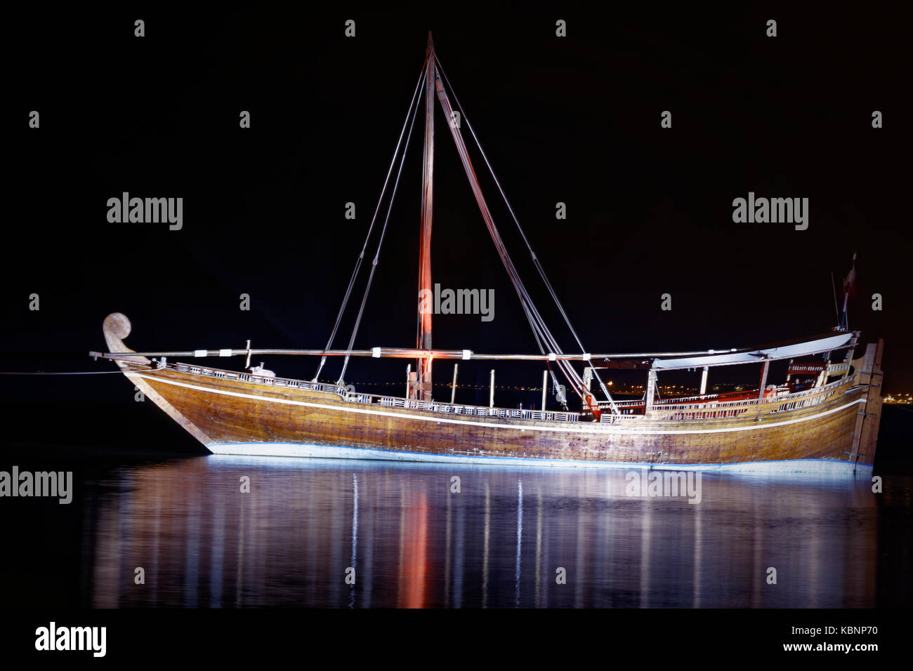Traditional wooden boat(dhow)  in Arabic gulf at nigh with reflection in water  in Doha, Qatar. Stock Photo