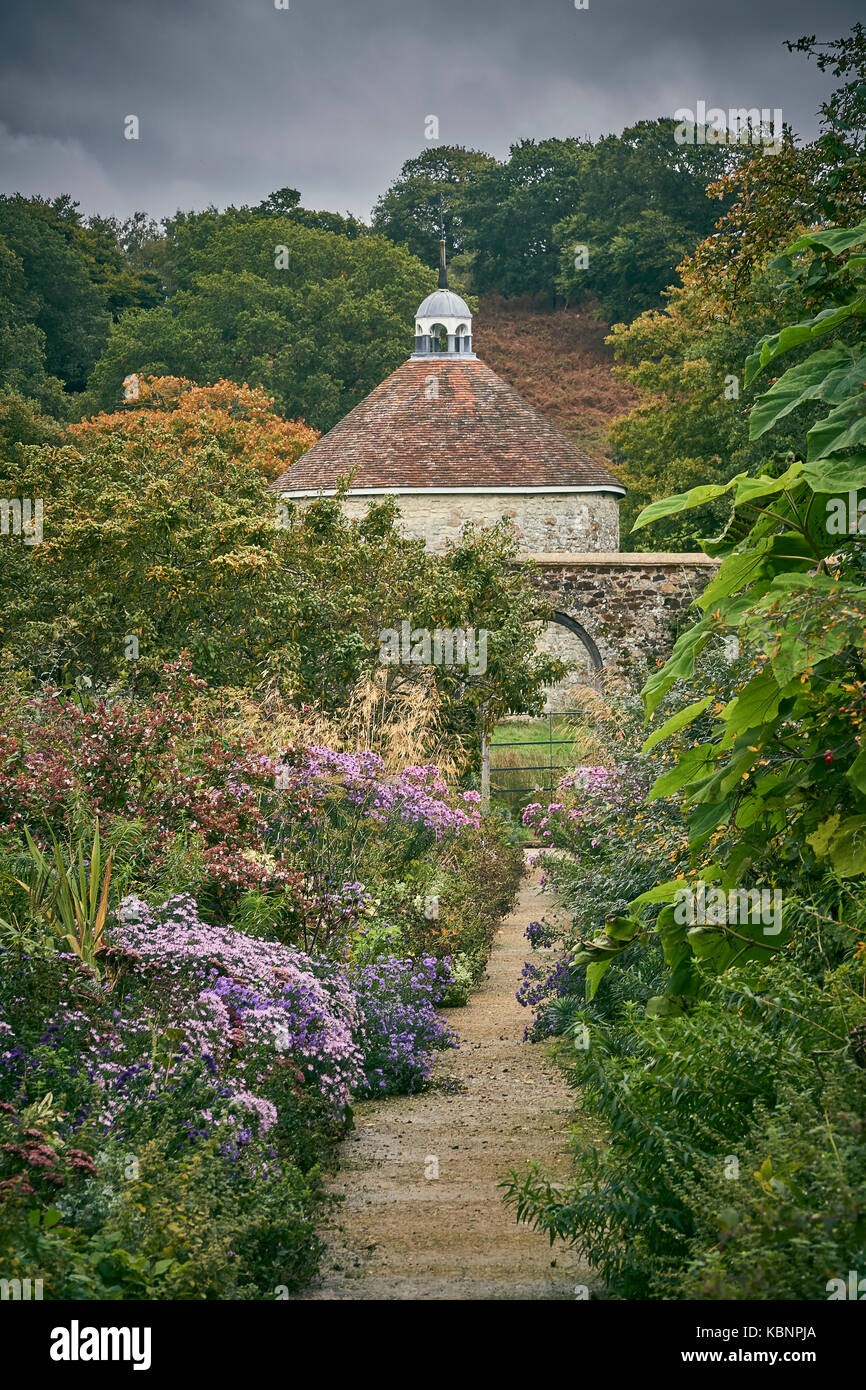 An informal gravel path through a large cottage garden with dovecote Stock Photo