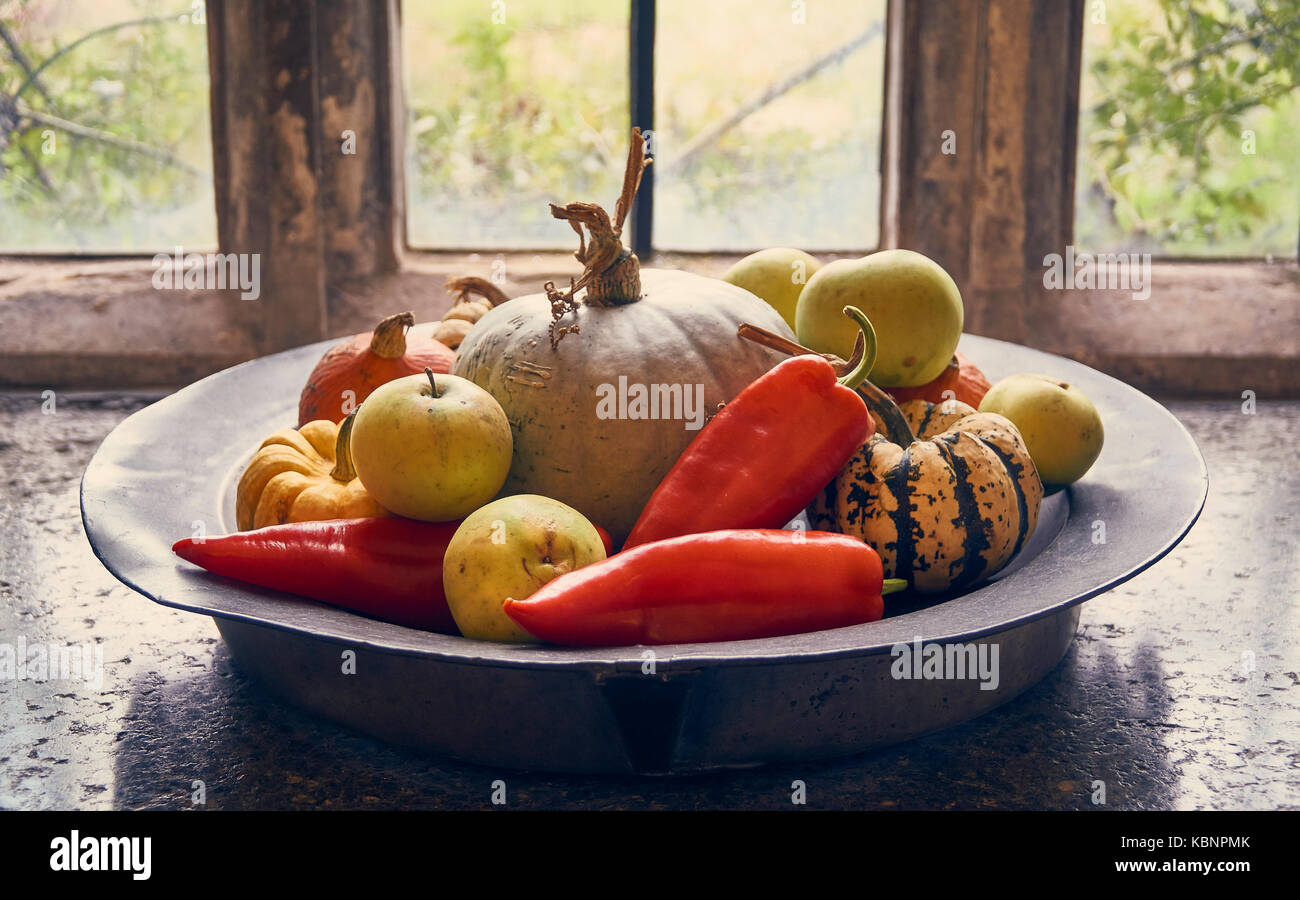 Collection of autumn country fruits in a rustic plate on an old window sill Stock Photo