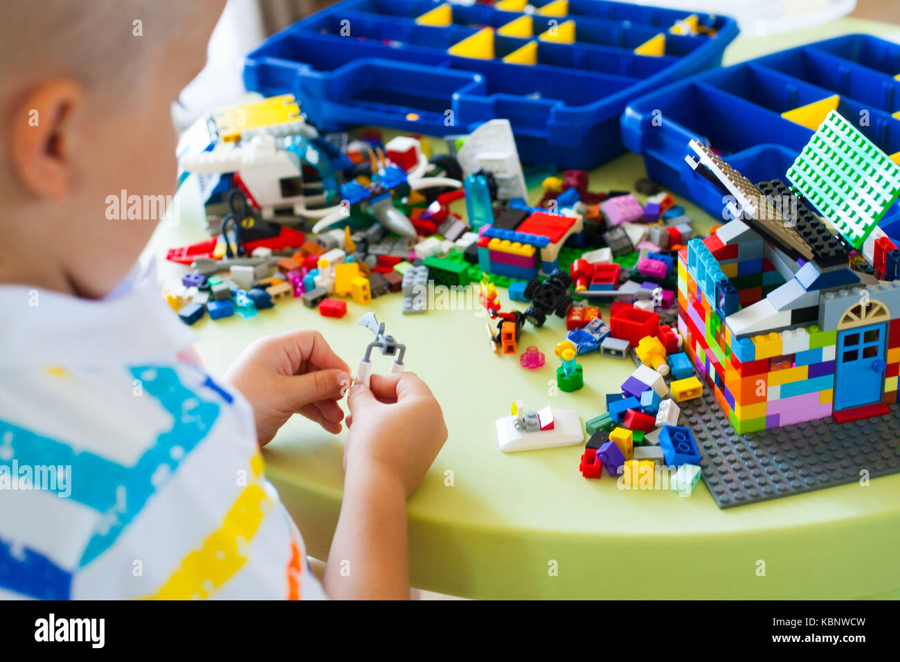 Little blond kid boy playing with lots of colorful plastic blocks ...