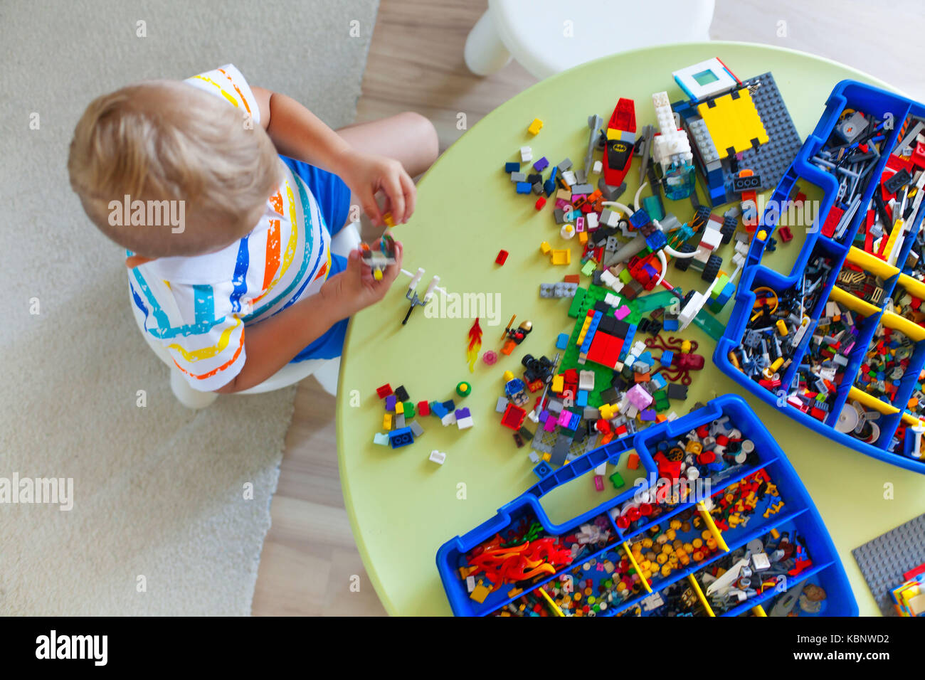 Little blond kid boy playing with lots of colorful plastic blocks ...