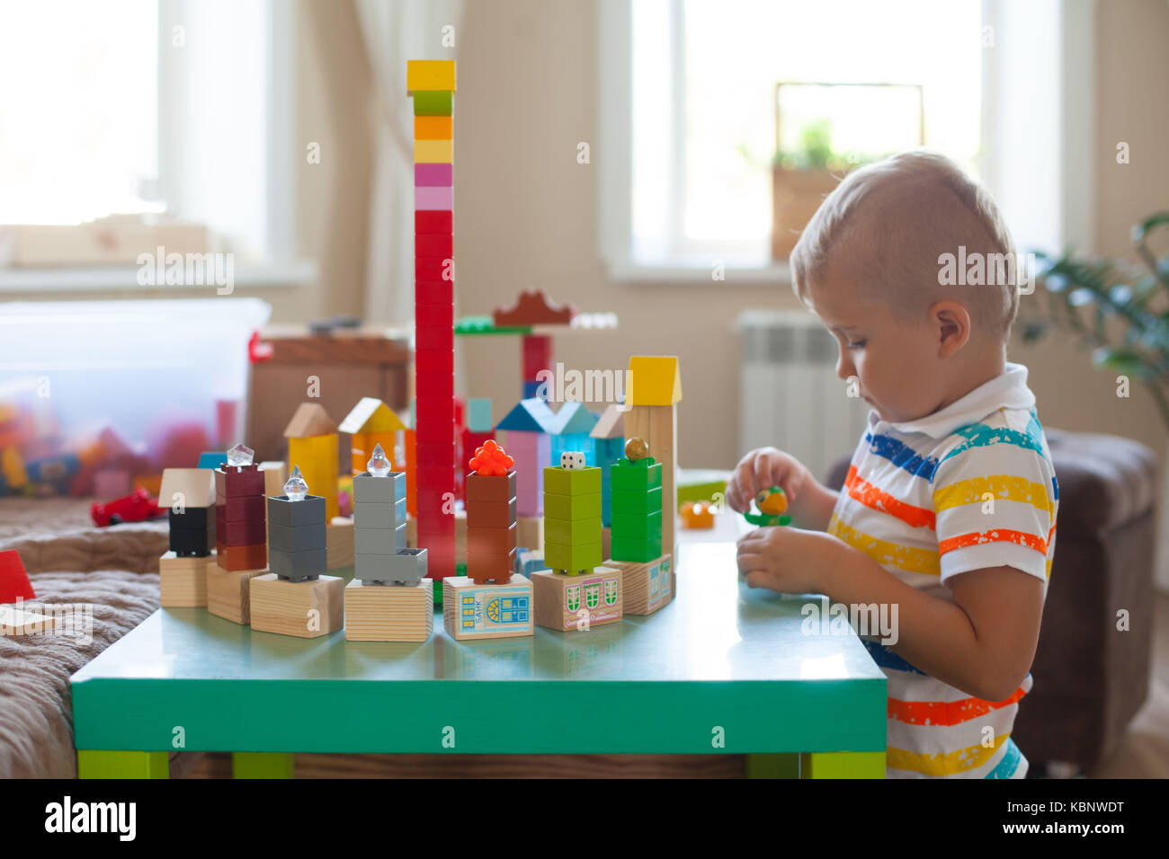 Little blond kid boy playing with lots of colorful plastic blocks ...