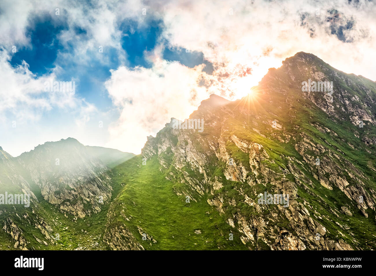 Sun flare bursting behind a mountain peak along Transfagarasan pass, in Romania Stock Photo