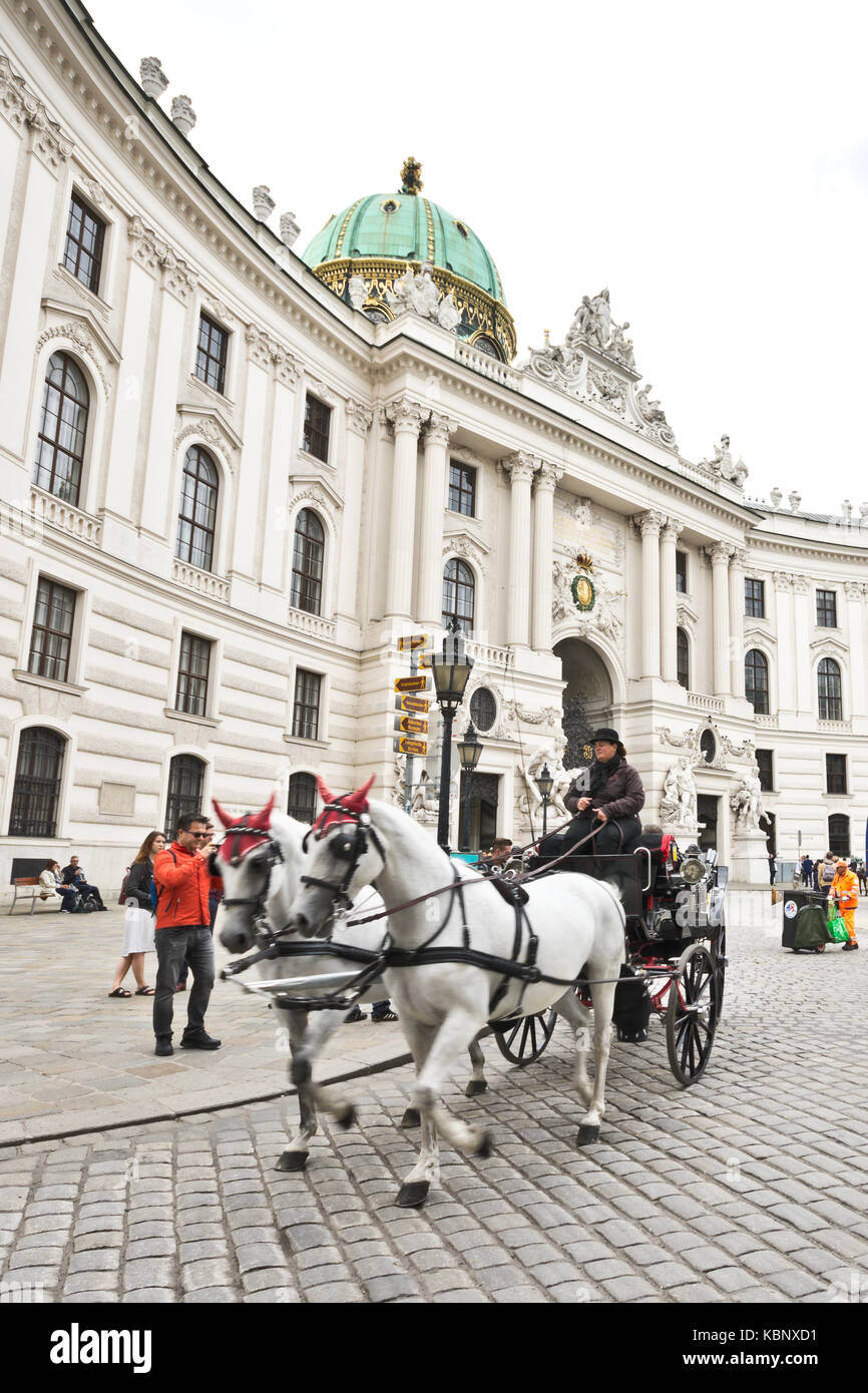 Famous horse-drawn carriage called fiaker passes by the Hofburg palace ...