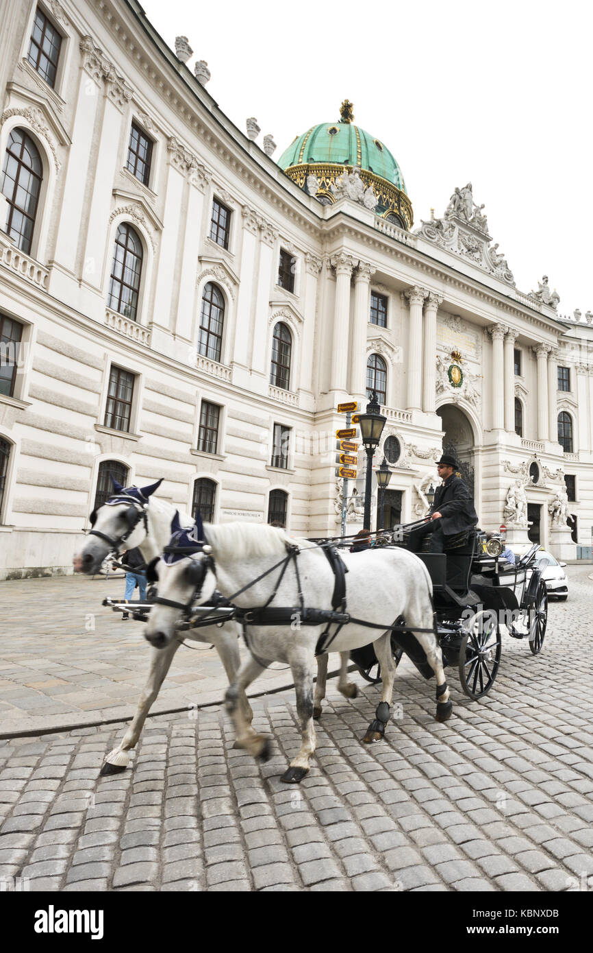 Famous horse-drawn carriage called fiaker passes by the Hofburg palace ...