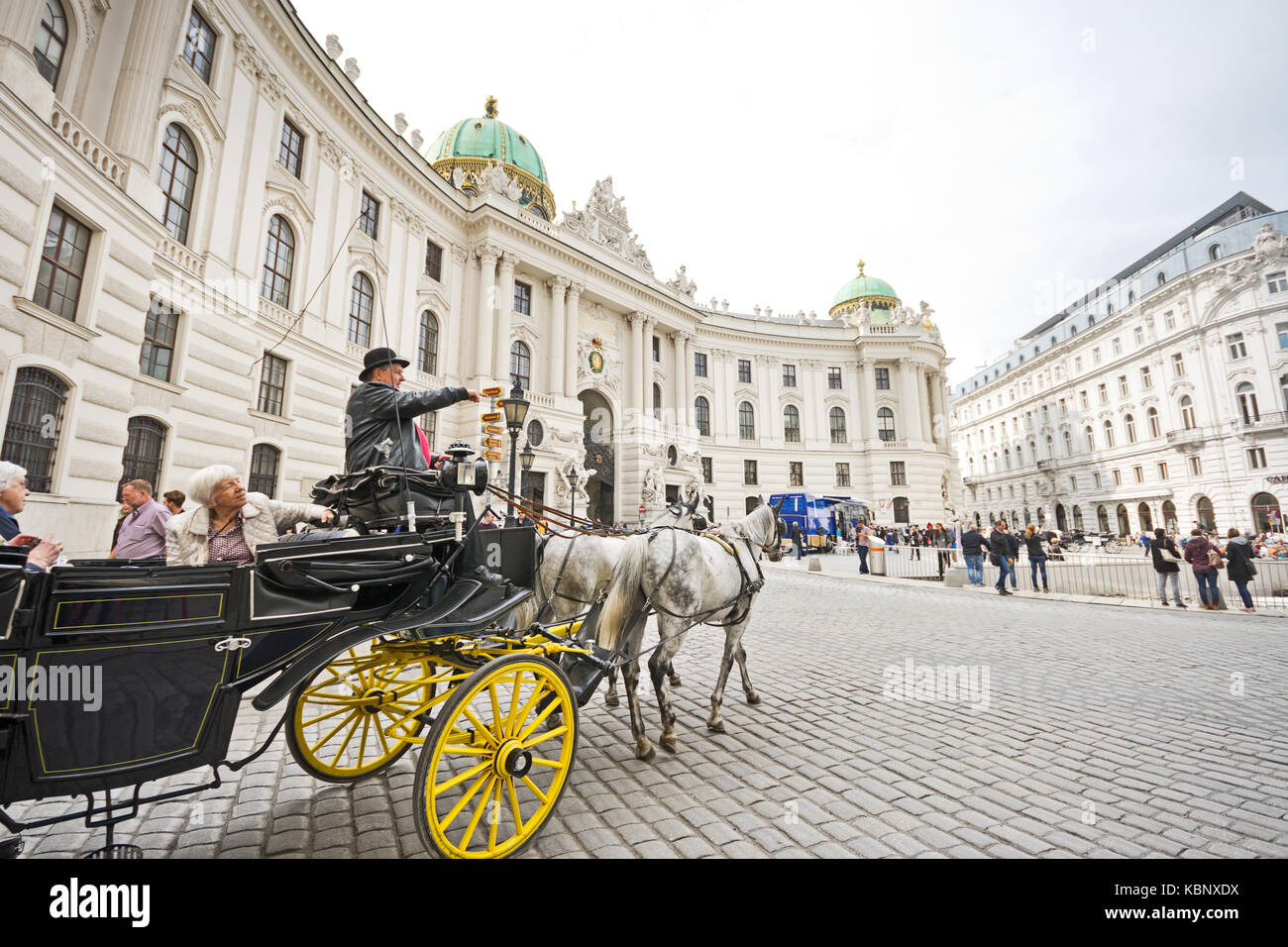 Famous horsedrawn carriage called fiaker passes by the Hofburg palace at Michaelerplatz in