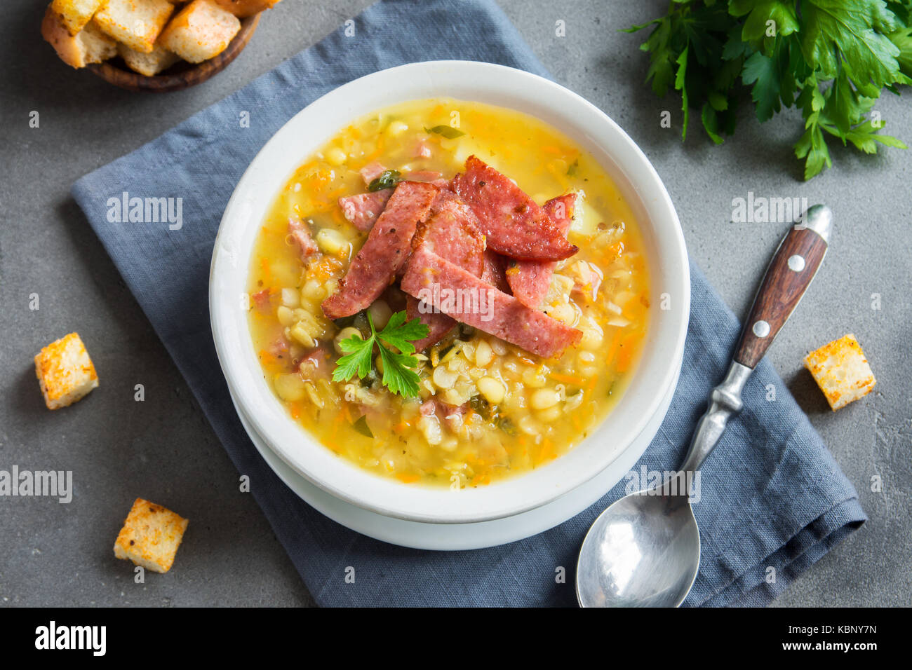Split pea soup with smoked ham and croutons on grey background. Healthy homemade thick split