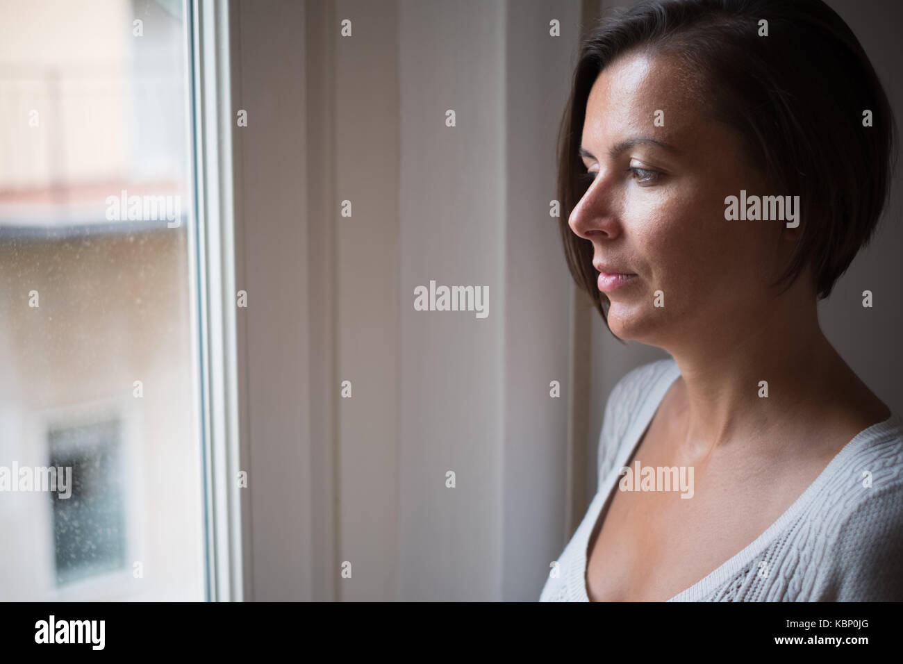 Handsome woman looking out the window Stock Photo - Alamy