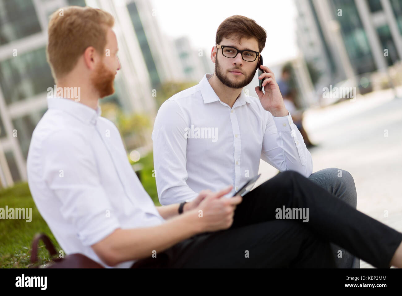 Business colleagues sitting on bench outdoors Stock Photo - Alamy